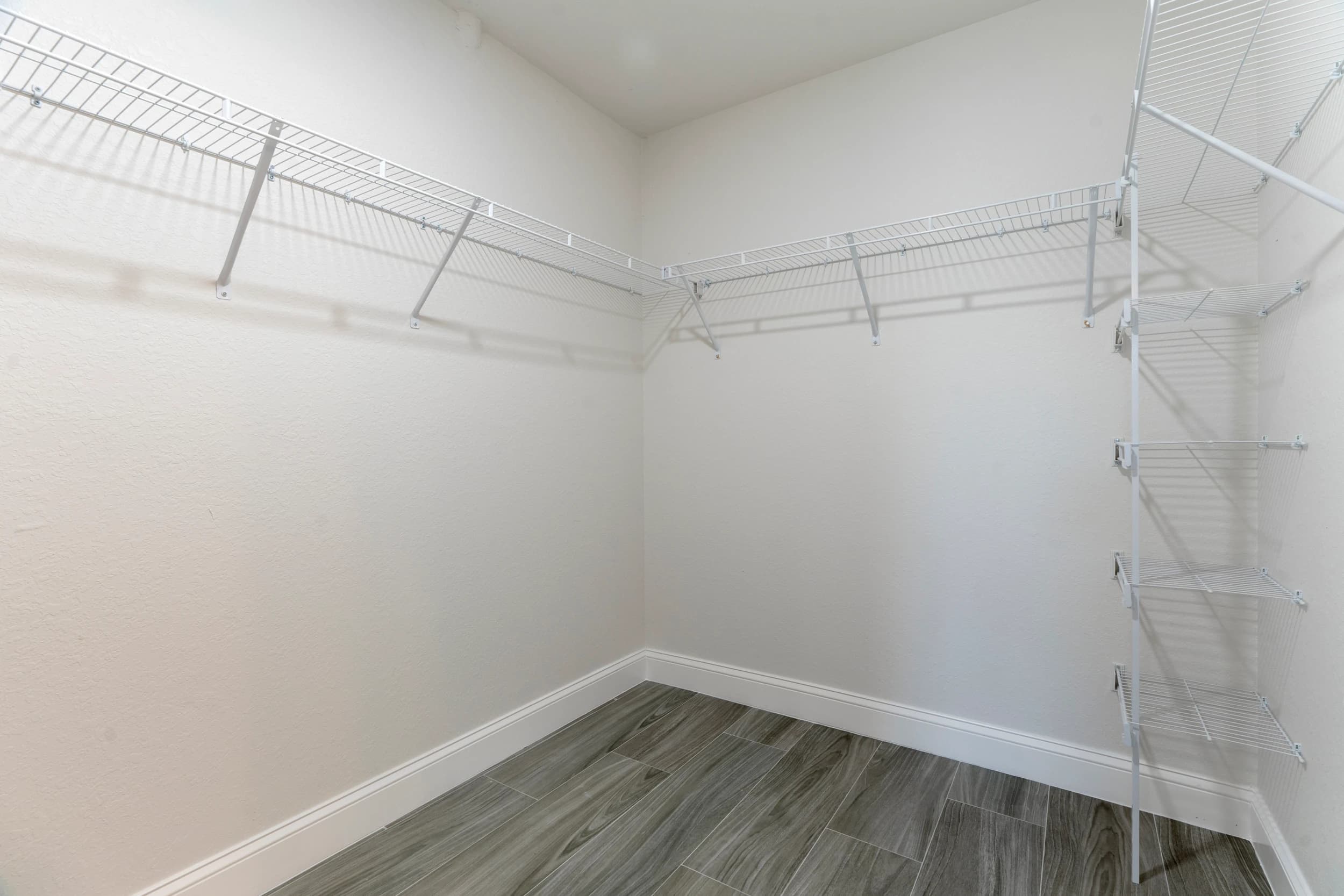 Spacious walk-in closet in a newly built home in Florida by Vreeland Roofing. Featuring white wire shelving for optimal storage and organization, this custom closet design maximizes space while maintaining a clean and modern look.