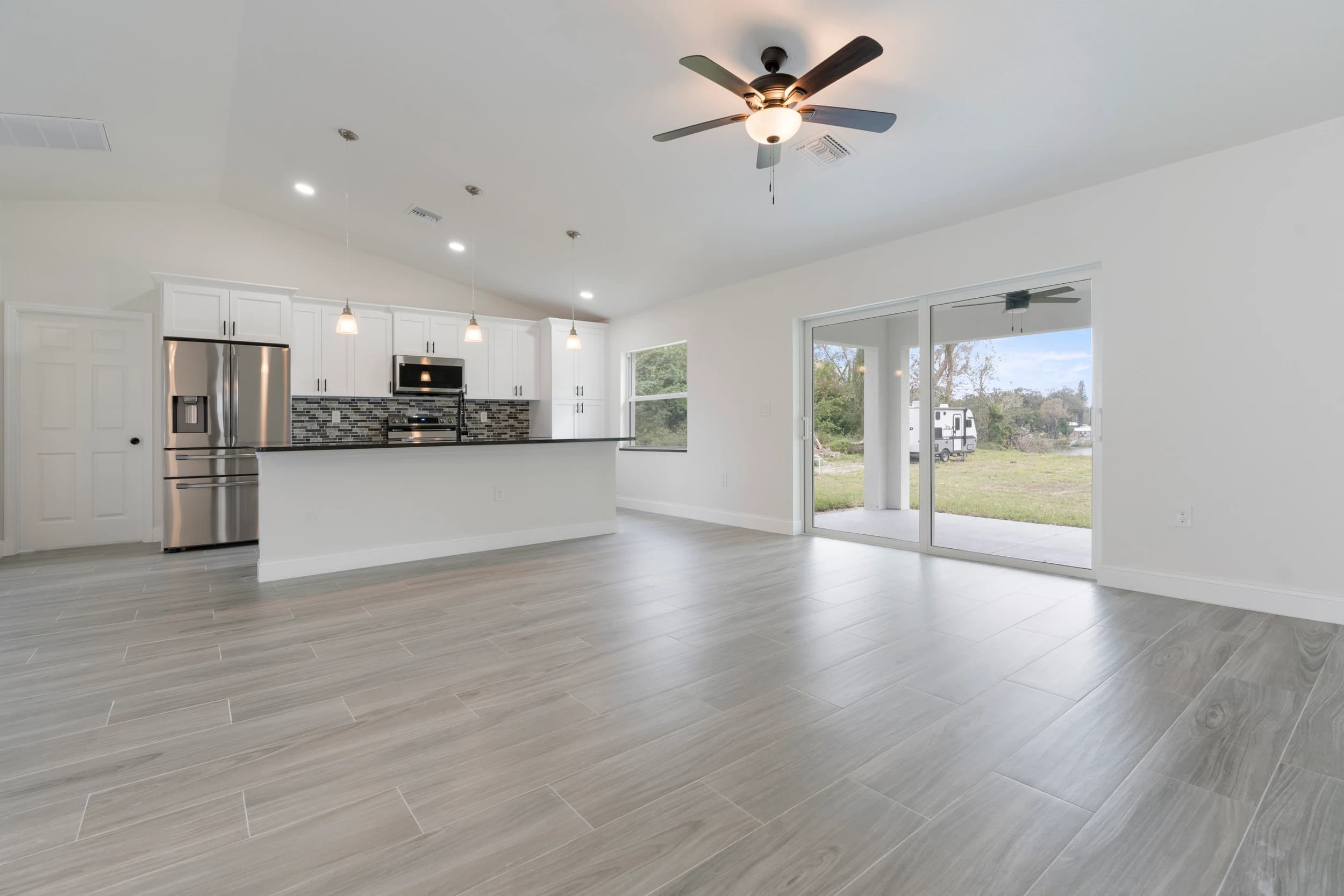 Open-concept living and kitchen area featuring a modern design, granite countertops, pendant lighting, and a ceiling fan, seamlessly blending style and functionality.